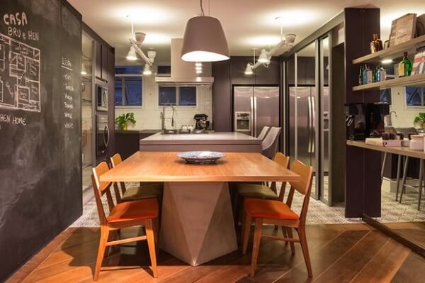 Sala de jantar integrada com a cozinha conta com mesa e cadeira de madeira