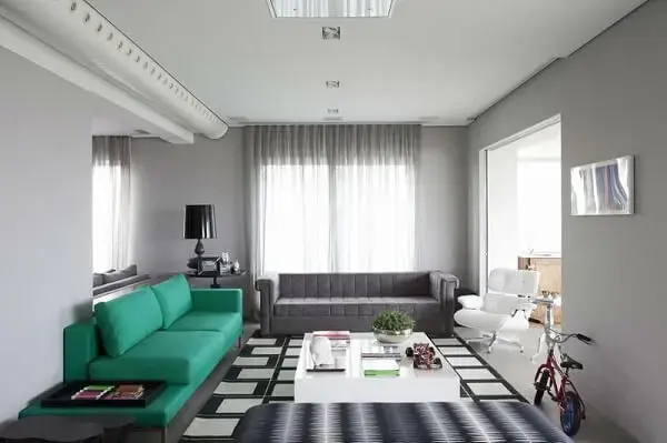 Sofá verde e tapete preto e branco encantam a decoração da sala de estar
