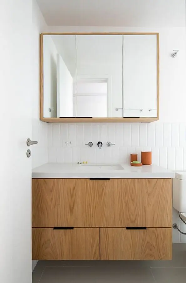 banheiro branco decorado com armário de banheiro de madeira suspenso Foto INÁ Arquitetura