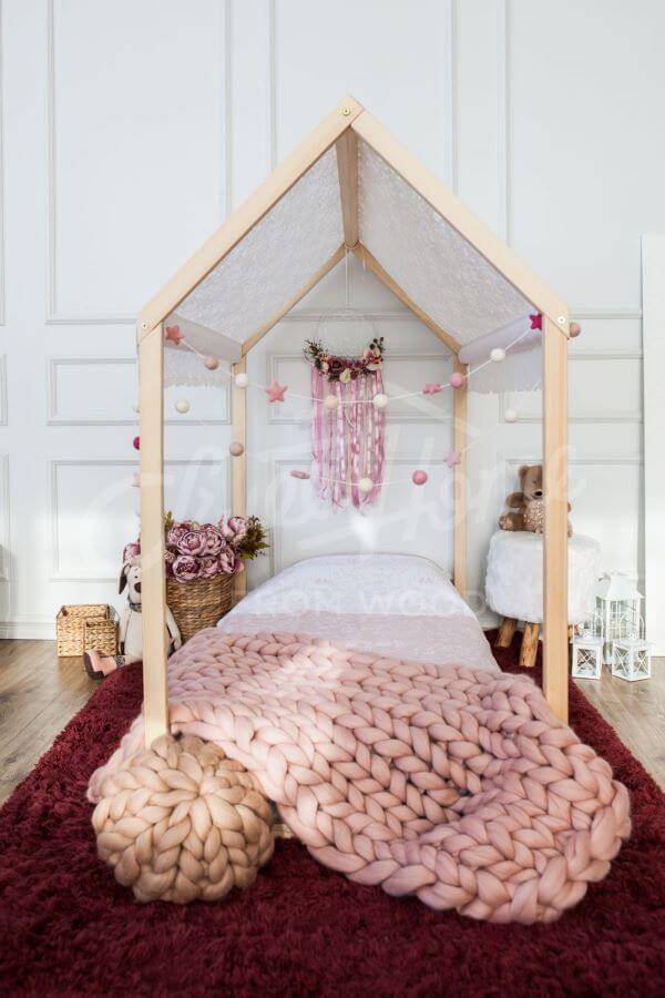 Cama casinha de madeira com manta rosa na decoração