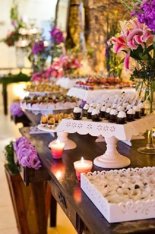decoração roomantica com arranjo de flores e pratos de bolos branco para mesa de guloseimas Foto Assetproject