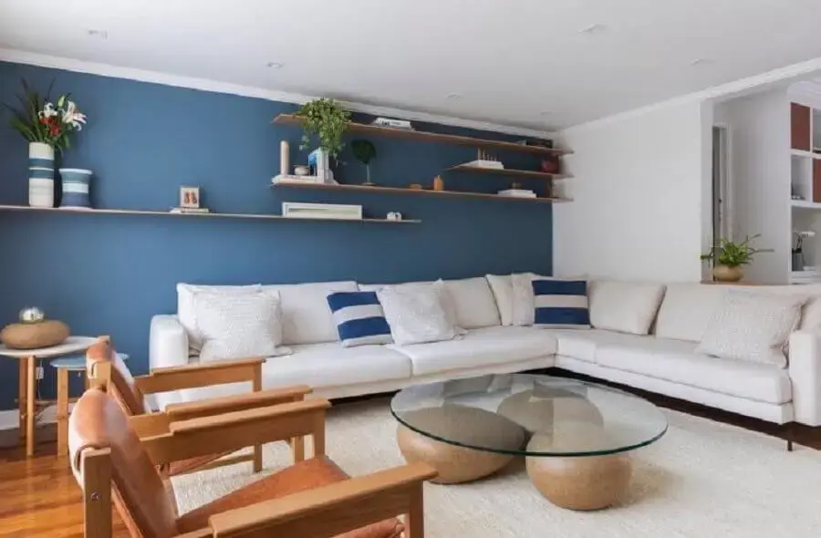 decoração sala ampla com parede azul sofá de canto branco e mesa de centro com base diferente Foto Voa Arquitetura