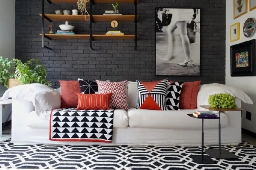 sala decorada com parede de tijolinho preto e sofá branco com almofadas coloridas Foto Mandril Arquitetura