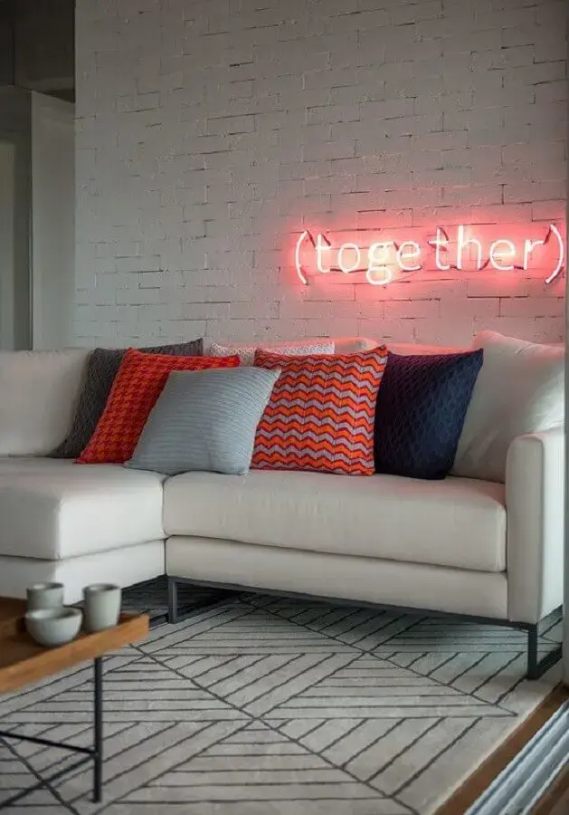 sala moderna decorada com luminária neon e sofá branco com almofadas coloridas Foto Casa de Valentina