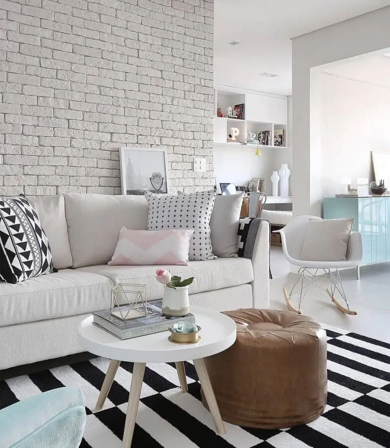 sofá branco de couro para sala decorada com parede de tijolinho e tapete listrado Foto Assetproject