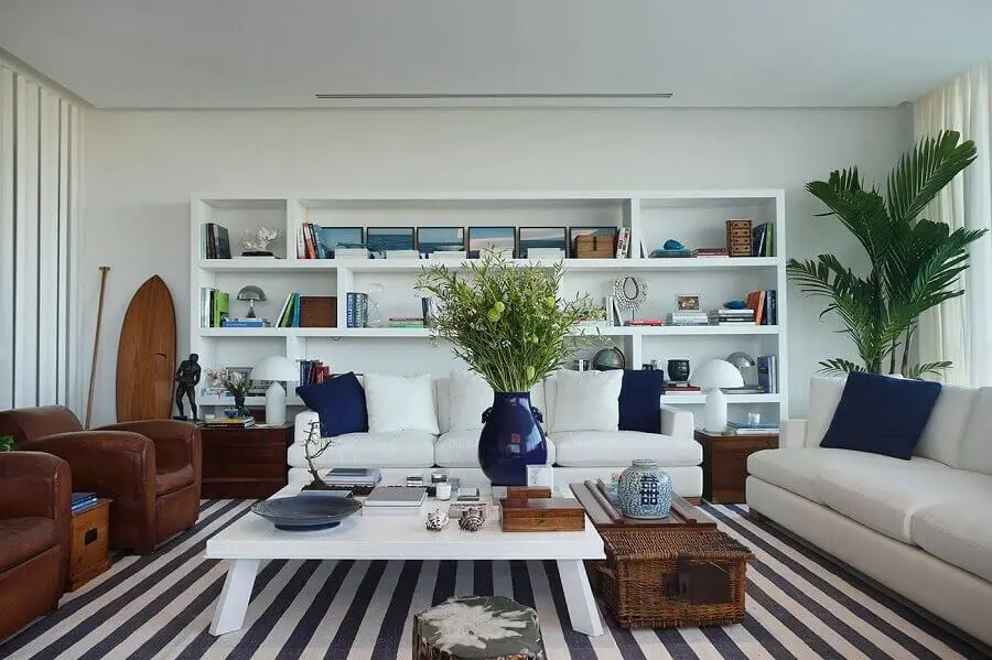 sofá branco para decoração de sala com tapete listrado e poltronas de couro Foto Radar Design