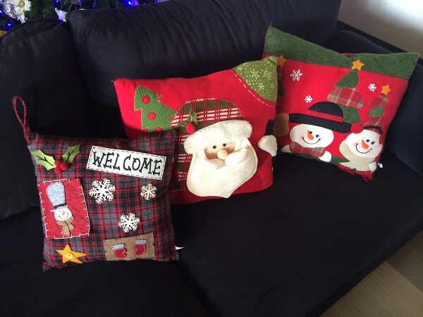 Sala de estar com sofá preto e almofadas de Natal