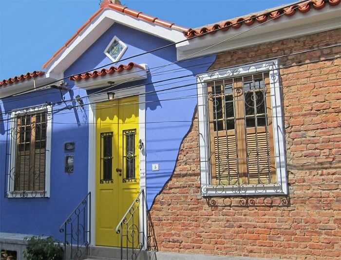 Cores de casas: fachada colorida com parede de tijolinho aparente