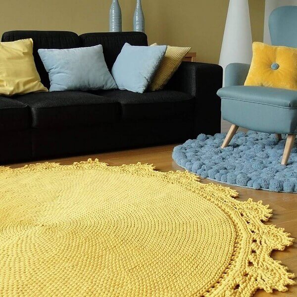 Sala de estar com sofá preto e tapete de crochê amarelo