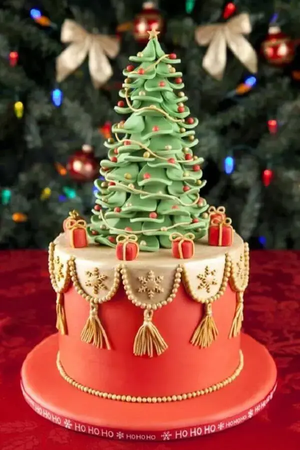 bolo de natal decorado com pasta americana e pequena árvore de natal no topo Foto LoveToKnow