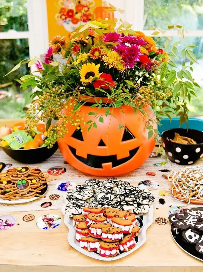 decoração de mesa dia das bruxas com arranjo de flores dentro de jack-o-lantern Foto CoachDecor