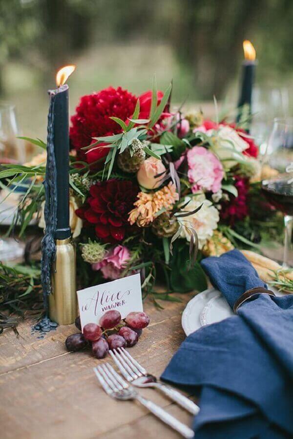 decoração para mesa de festa com castiçal dourado e vela preta próximo a arranjo de flores Foto L’idée Déco