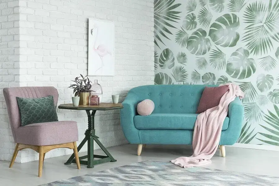sala de estar decorada com sofá azul e papel de parede com folhagens 