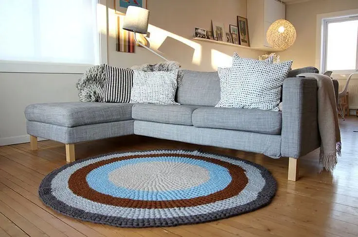 sofá para apartamento - tapete de crochê, sofá cinza e almofadas brancas 