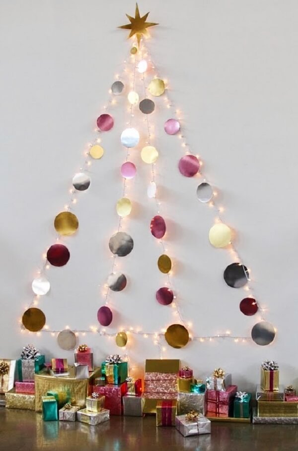 A árvore de Natal na parede foi feita com pisca pisca e bolinhas metálicas