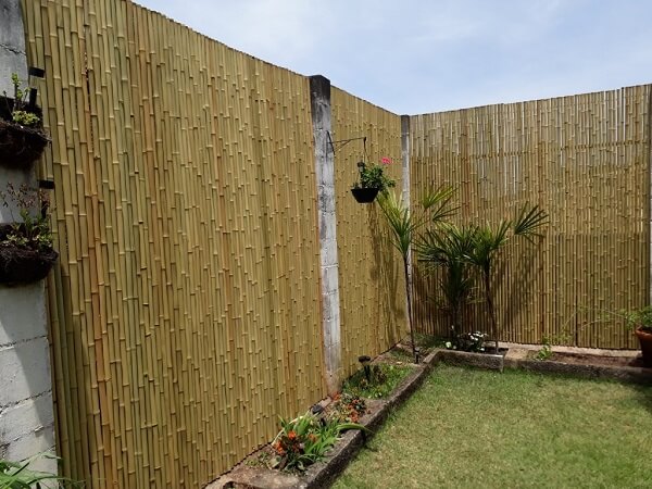 Jardim externo delimitado com cerca de bambu