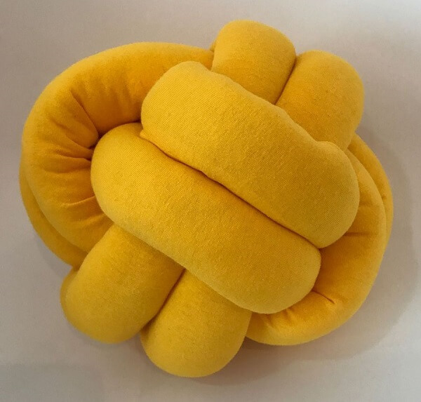 Almofada do tipo nó na cor amarela traz alegria para a decoração