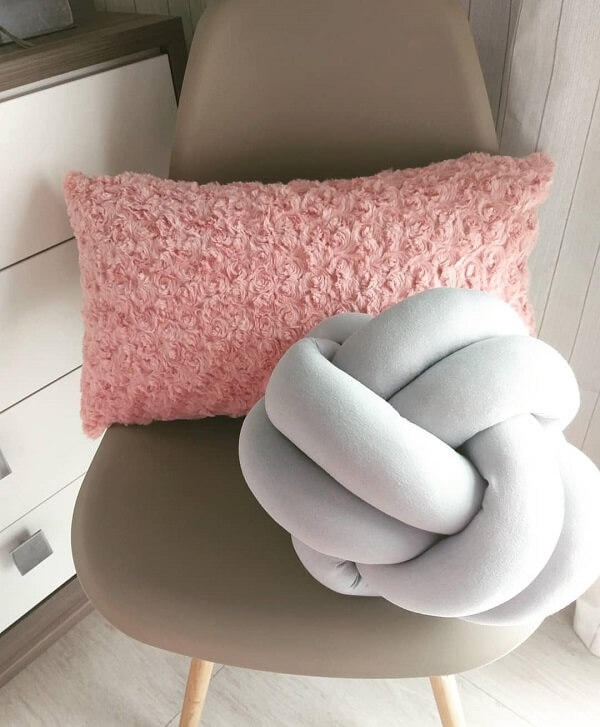 A almofada de nó em tom cinza claro combina facilmente com a almofada rosa