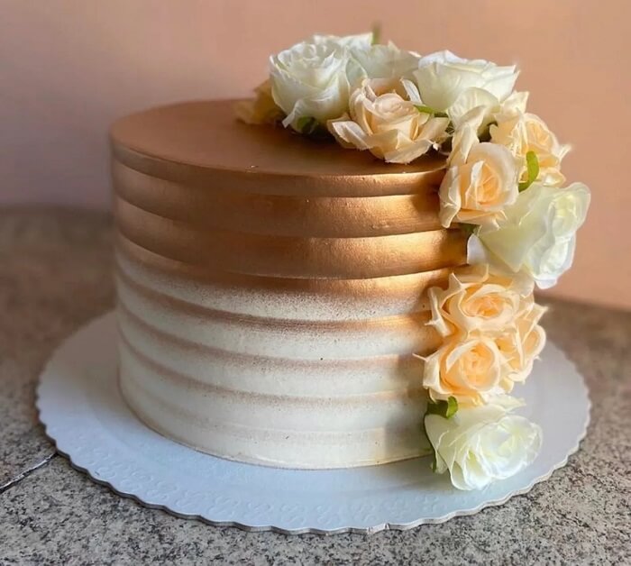 As rosas em branco e dourado trazem o toque delicado para o bolo de bodas de ouro