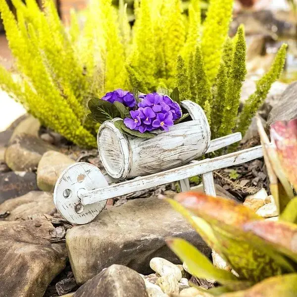 Invista em enfeites para jardim em tamanho miniatura como esse carrinho de mão barril