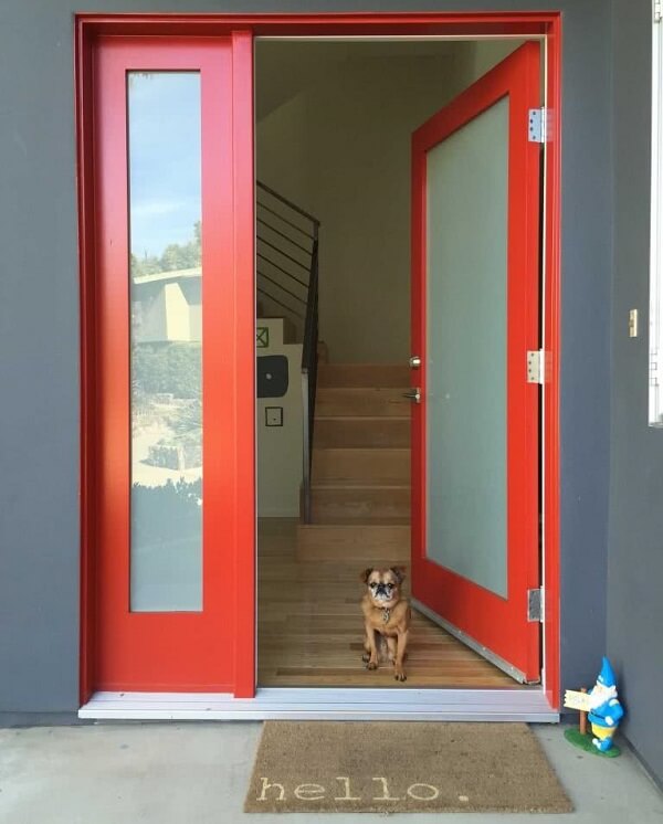 Hall de entrada com porta de vidro jateado e acabamento em tom vermelho