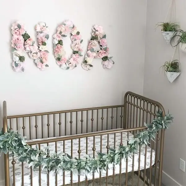 Letras decorativas com flores se conectam com os demais elementos do quarto do bebê