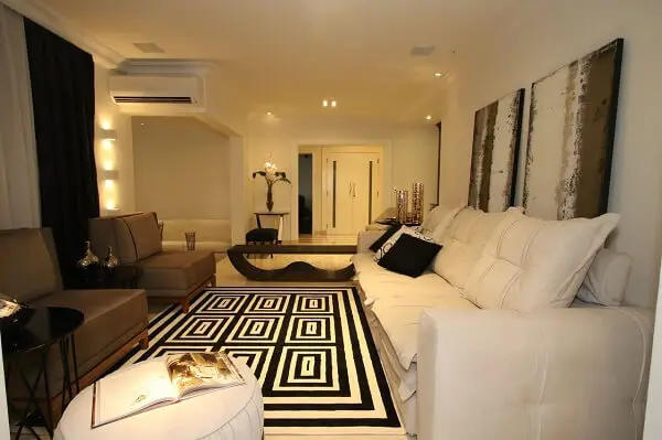 Living com sofá de três lugares e tapete geométrico preto e branco