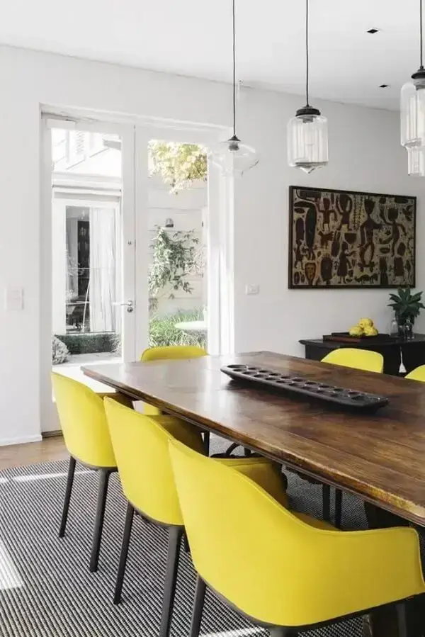 Mesa de jantar de madeira com cadeira amarela e pé em acabamento preto