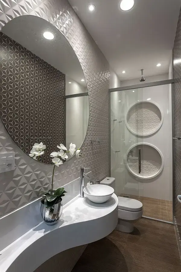 Parede 3D e chuveiro de teto se destacam na decoração do banheiro
