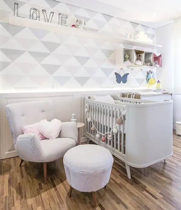 Quarto de bebê decorado com papel de parede geométrico e poltrona cinza de amamentação