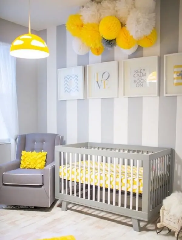 Quarto de bebê decorado com papel de parede listrado e poltrona cinza