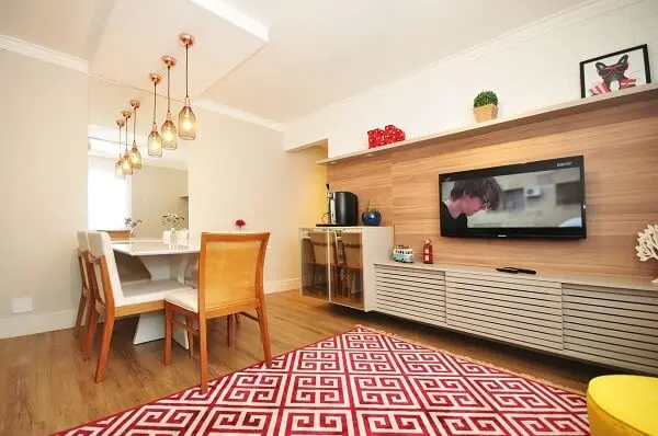 Sala com decoração branca, móveis de madeira e tapete geométrico vermelho