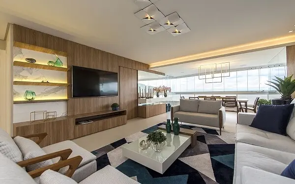 Sala de estar ampla com painel para Tv de madeira e tapete geométrico colorido