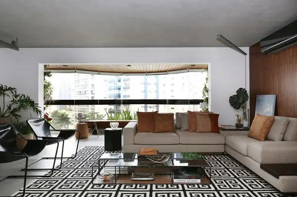 Sala de estar ampla com sofá de canto bege e tapete geométrico