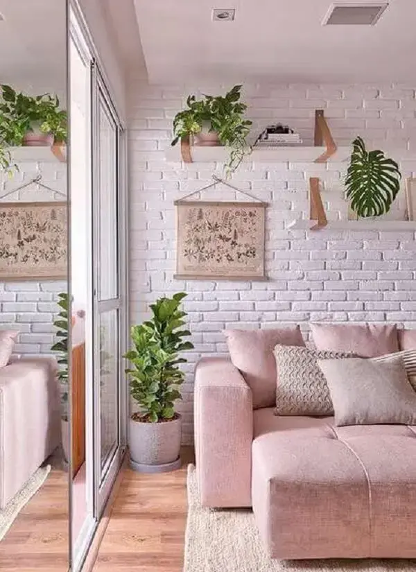 Sala de estar com parede de tijolinho e sofá retrátil rosa claro