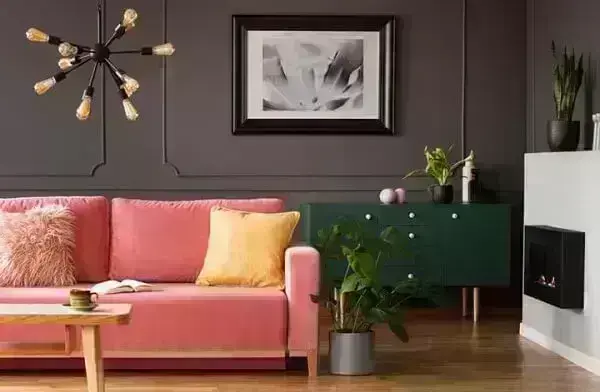 Sala de estar com pendente metálico e sofá rosa