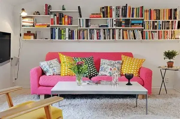 Sala de estar com prateleiras para livro e sofá rosa