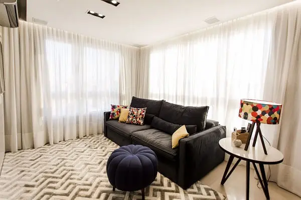 Sala de estar com sofá preto e tapete geométrico