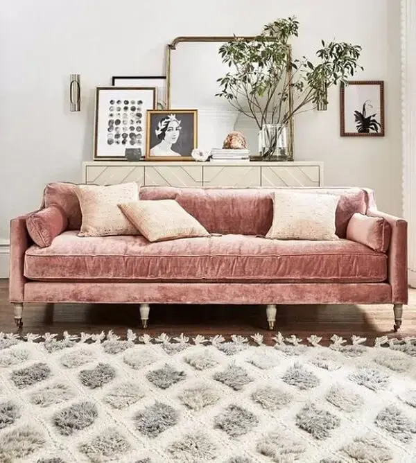 Sala de estar com sofá rosa claro feito em tecido aveludado