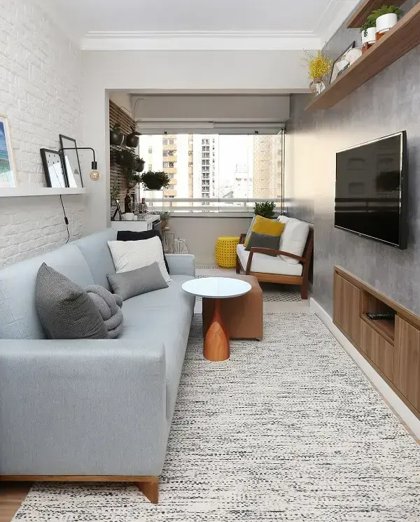 Sala de estar compacta com parede de cimento queimado e sofá azul bebê