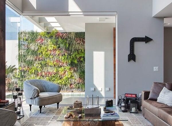 Sala de estar decorada com jardim vertical e poltrona cinza