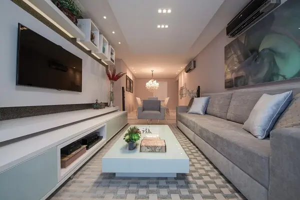 Sala de estar decorada com tapete geométrico, sofá e poltrona cinza