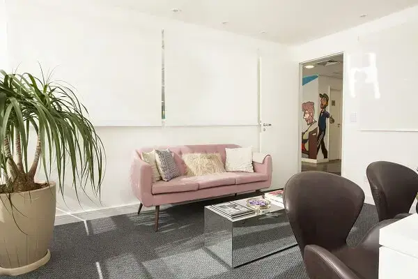 Sala de recepção com sofá rosa e mesa de centro espelhada