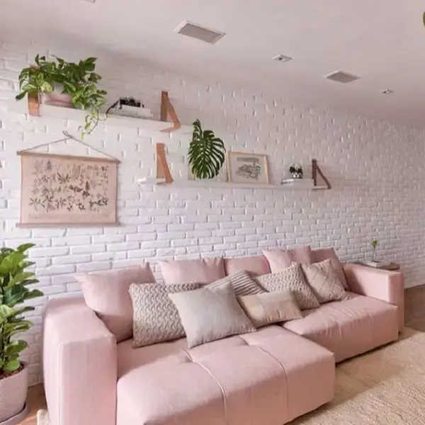 Sofá retrátil rosa claro e parede de tijolinho branca