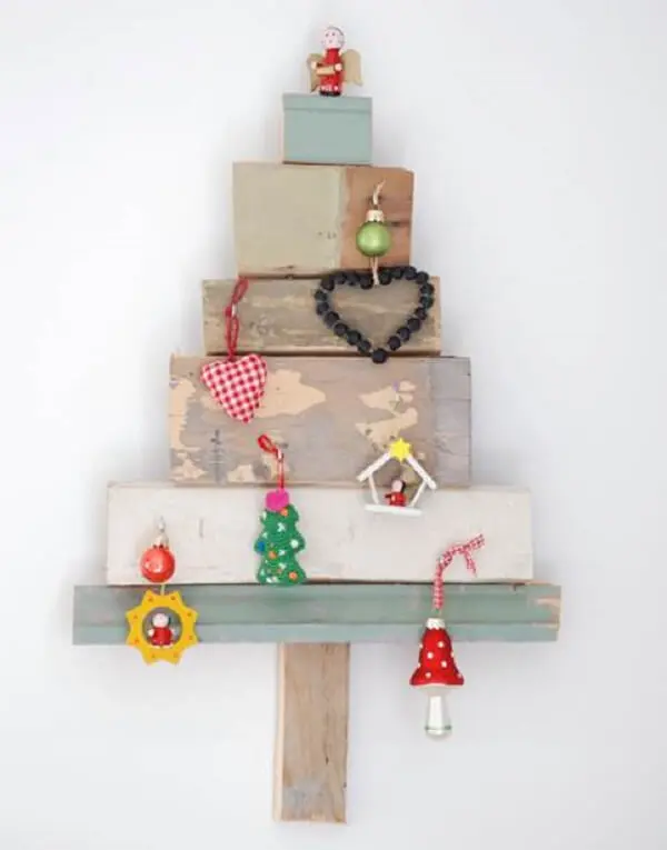 Tocos de madeira e enfeites formam a árvore de Natal na parede