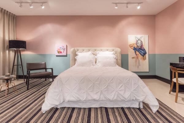 Decoração quarto de casal quarto rosa com faixa turquesa e cama arrumada