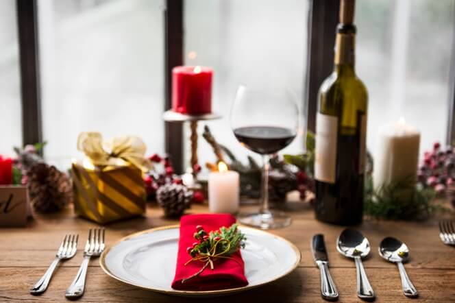 Mesa de natal com guardanapo vermelho, taça de vinho e velas