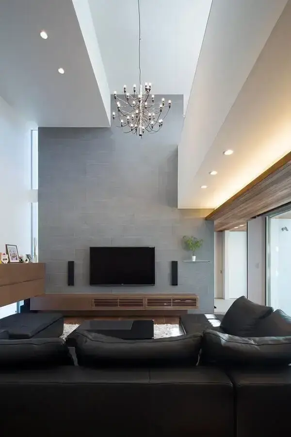 sala moderna decorada com sofá preto e rack de madeira Foto Assetproject