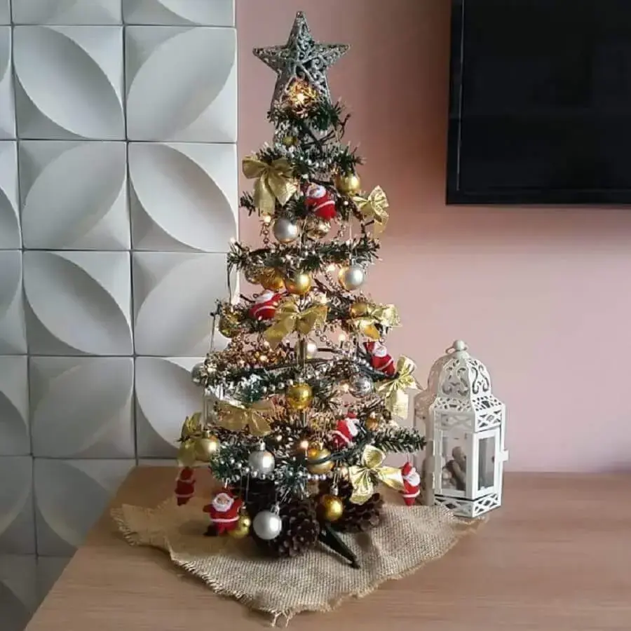 árvore de natal pequena decorada com bolas e laços dourados e pequenos papais noeis Foto Criatividarte