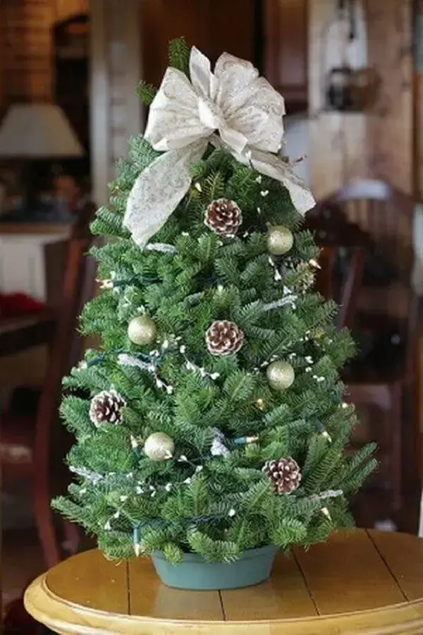 árvore de natal pequena decorada com pinhas e laço no topo Foto Loris Decoration
